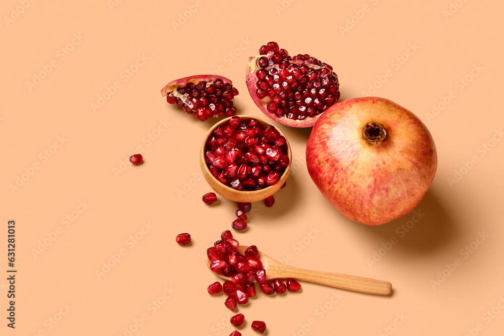 Fresh pomegranates and bowl with seeds on orange background