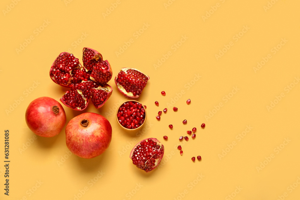 Fresh pomegranates and bowl with seeds on yellow background