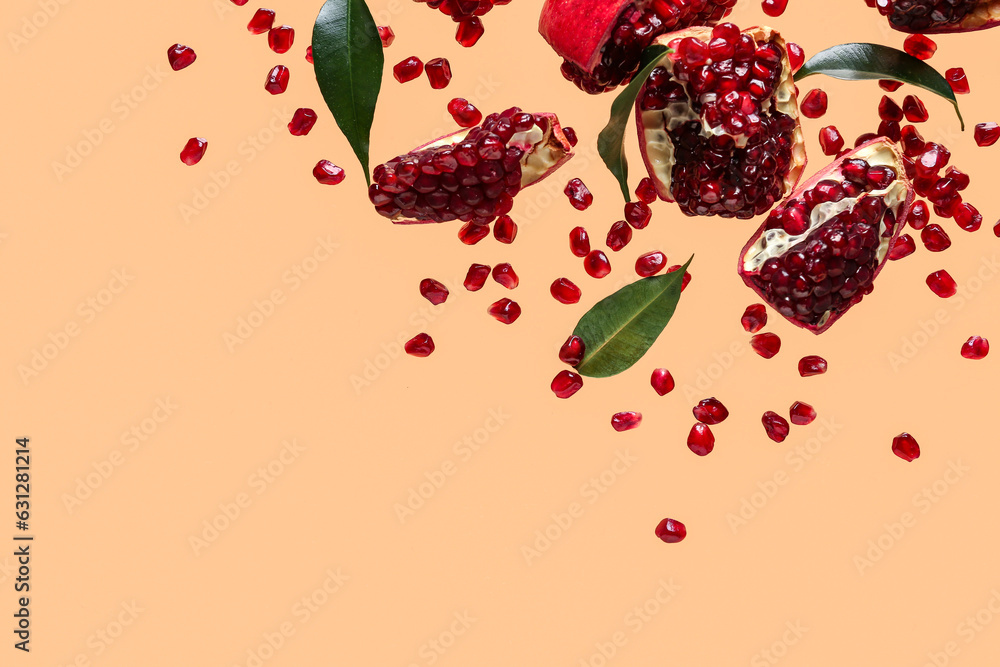 Flying fresh pomegranates with seeds and leaves on orange background