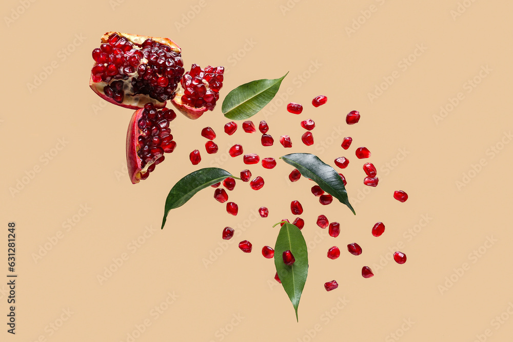 Flying fresh pomegranate with seeds and leaves on orange background