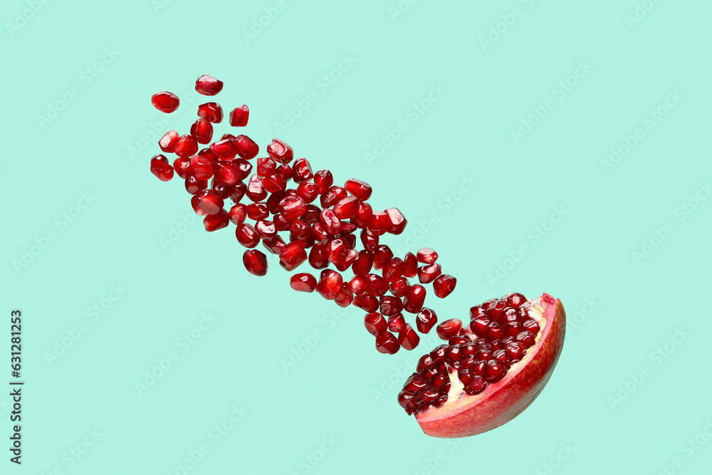 Flying fresh pomegranate with seeds on turquoise background