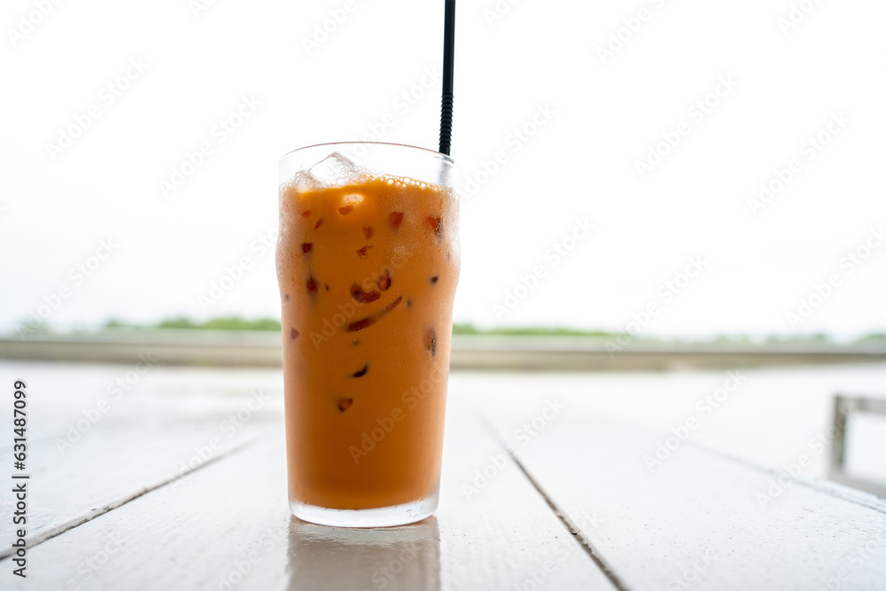 A Fresh Glass of ice milk tea, Sweet juice ice Tea dessert on a wooden saucer in the garden farm