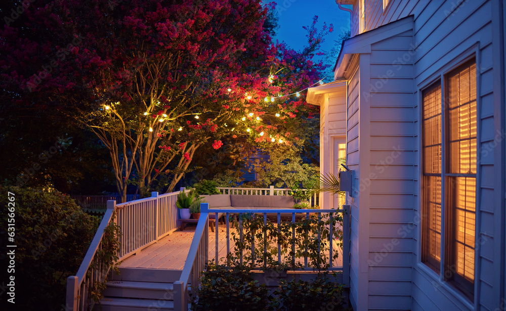 beautifully lit exterior of traditional house with wooden terrace and blooming crape myrtle in summe