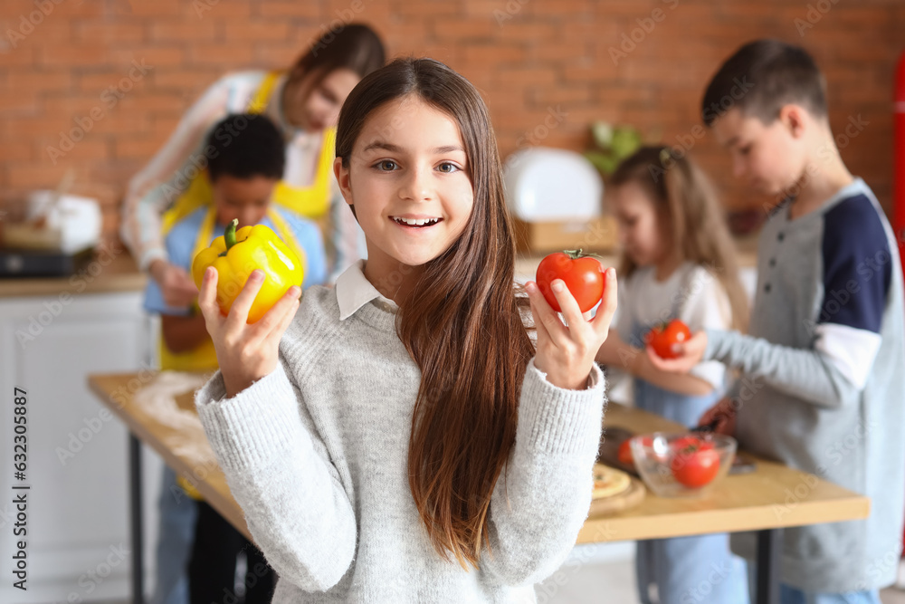 Little girl with vegetables during cooking class in kitchen