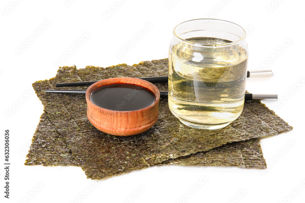 Glass of rice vinegar, soy sauce and nori sheets on white background