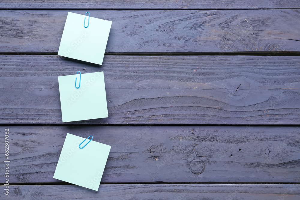 Sticky notes with paper clips on blue wooden background