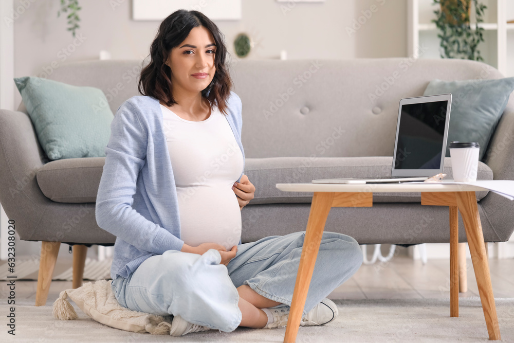 Young pregnant woman working with laptop at home