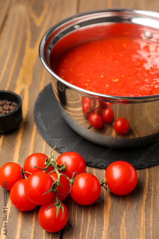 Saucepan with tasty tomato sauce and fresh vegetables on wooden background