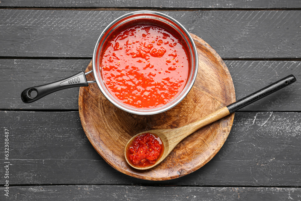 Saucepan with tasty tomato sauce on dark wooden background