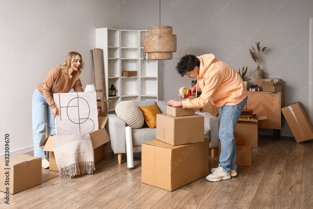 Young couple packing things in room on moving day