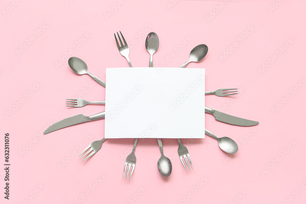 Frame made of blank card and stainless steel cutlery on pink background