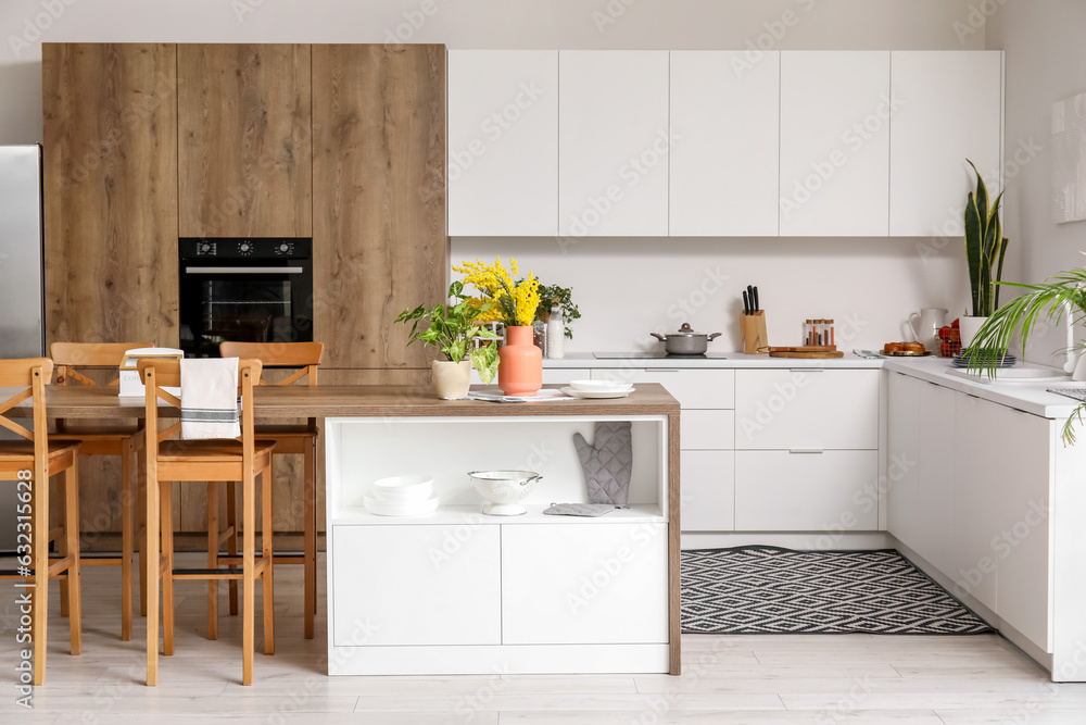 Interior of light kitchen with white counters, island and integrated oven