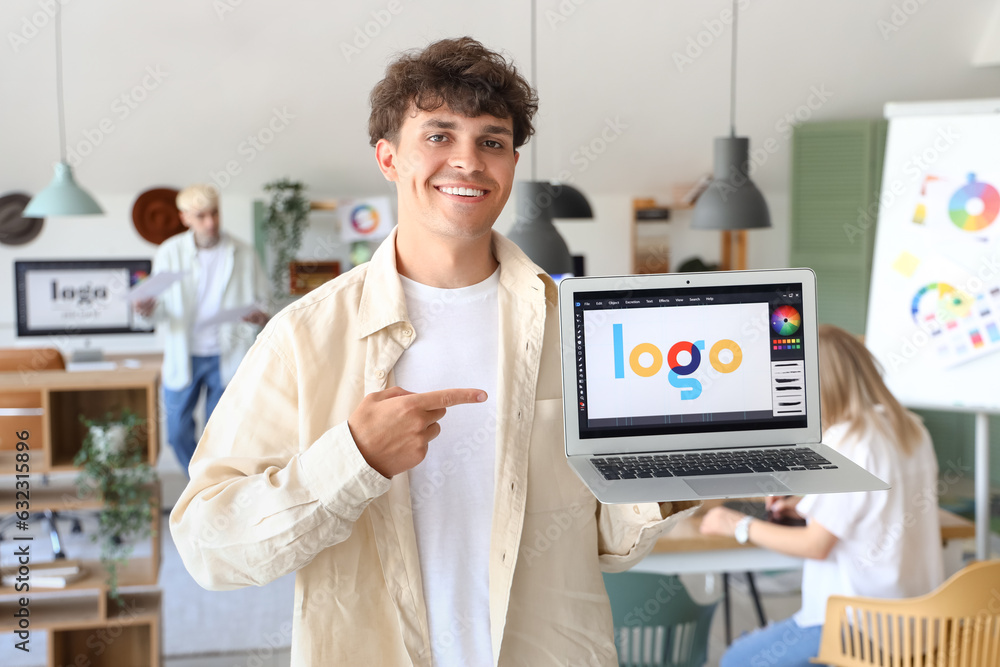 Male graphic designer pointing at laptop in office