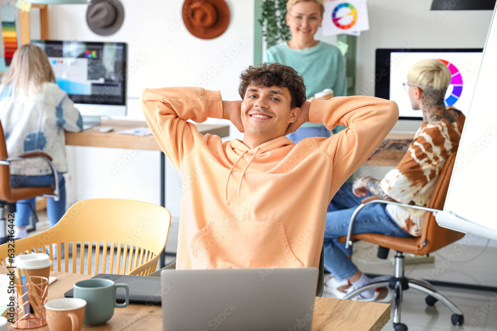 Male graphic designer resting at table in office