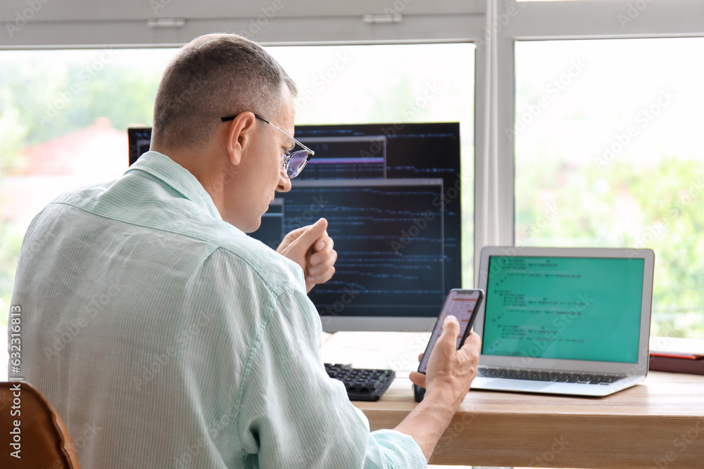 Mature male programmer sitting in office at his workplace