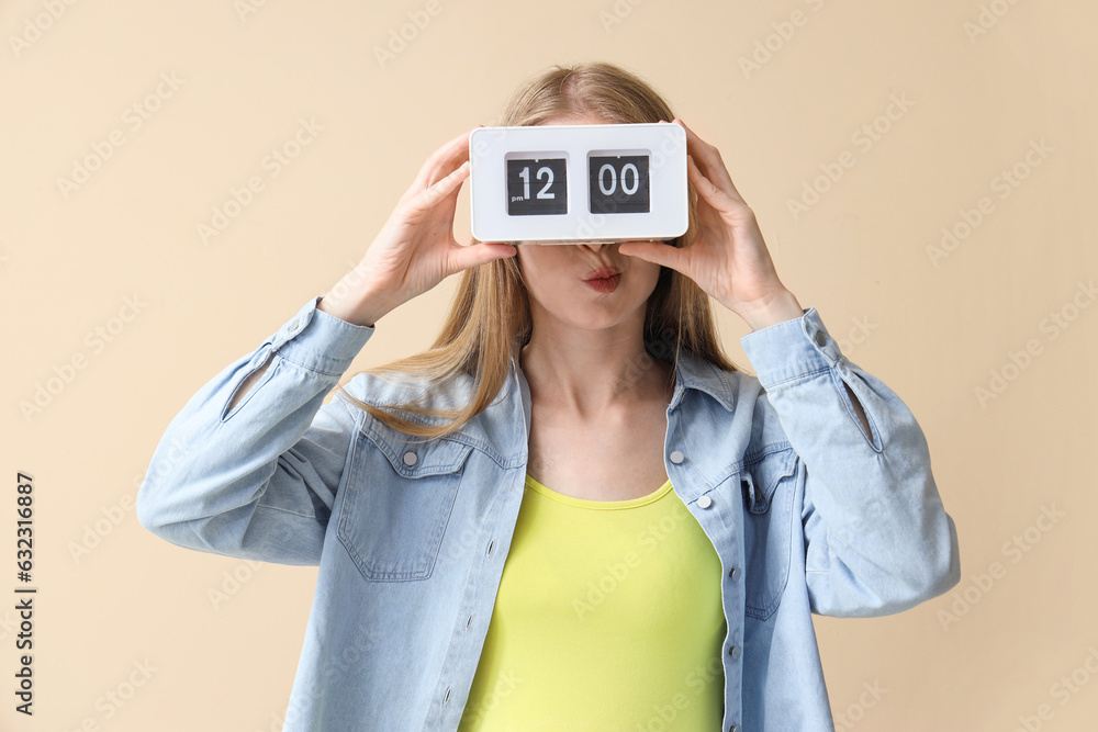 Young woman with clock on beige background. Deadline concept