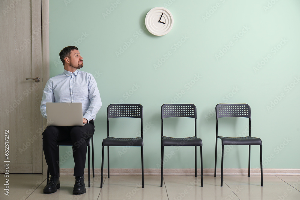 Male applicant with laptop waiting for job interview in room