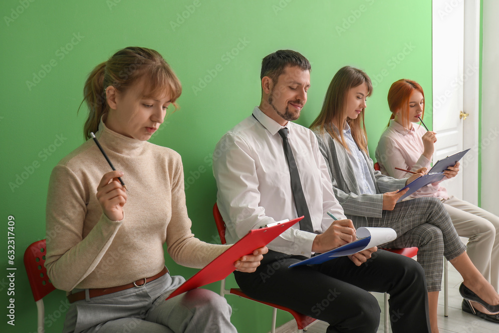 Young applicants with clipboards waiting for job interview in room