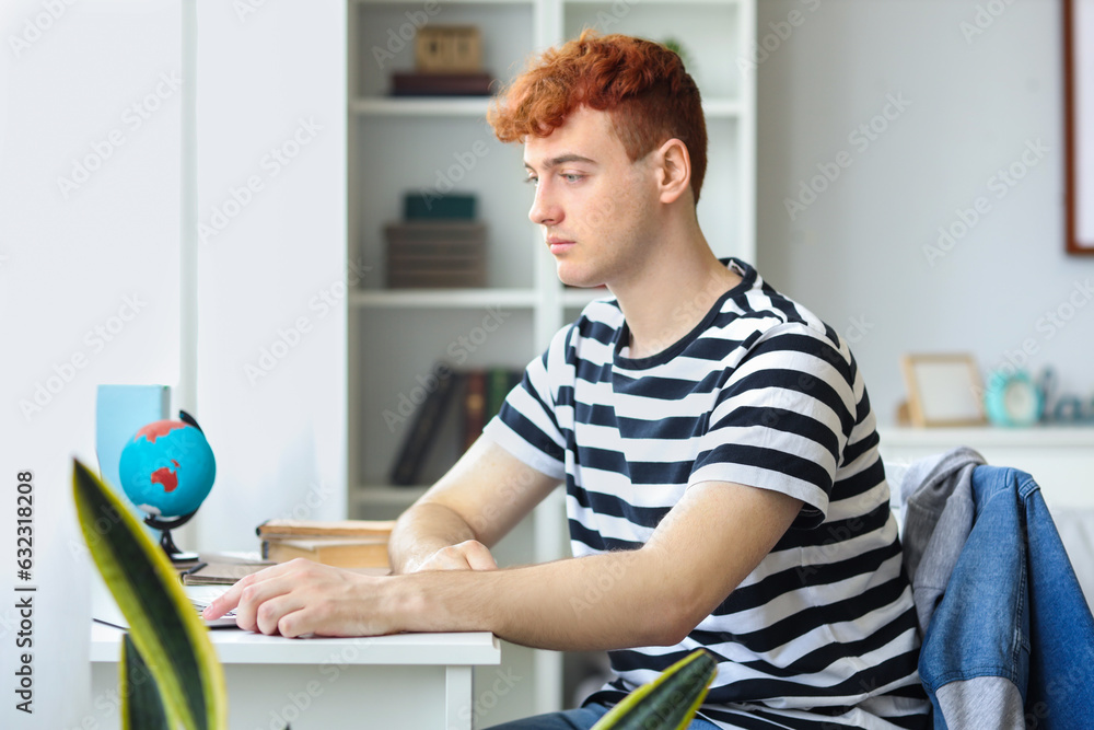 Young redhead man studying at home