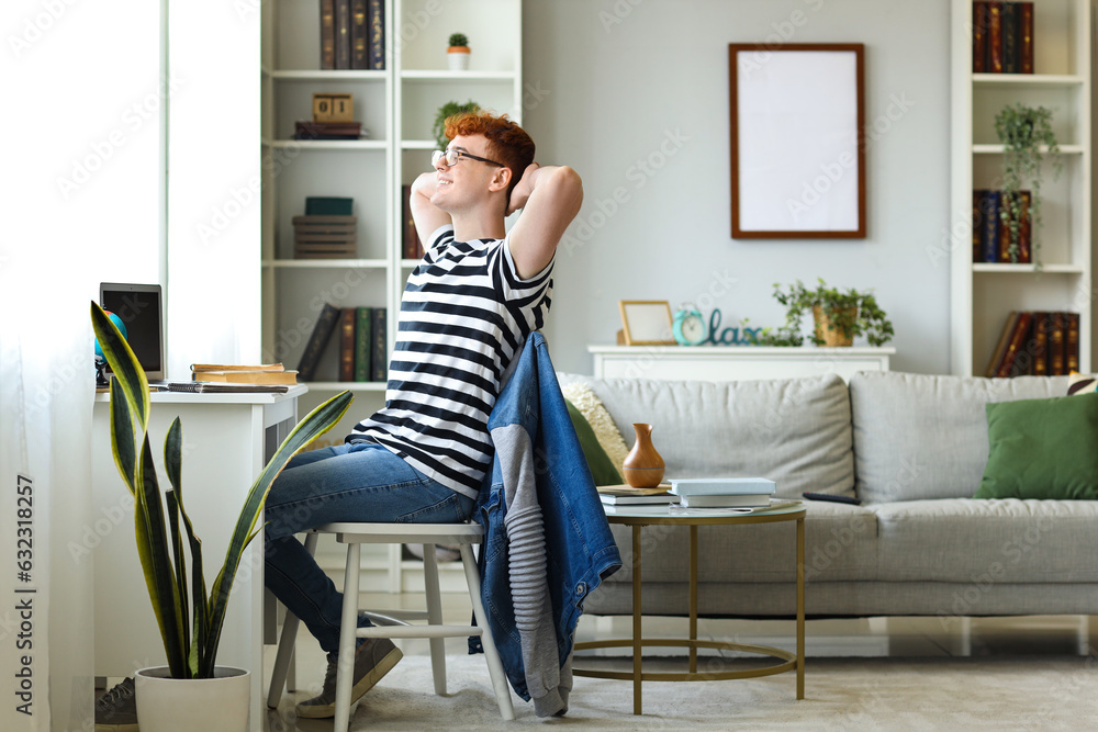 Young redhead man resting in chair at home