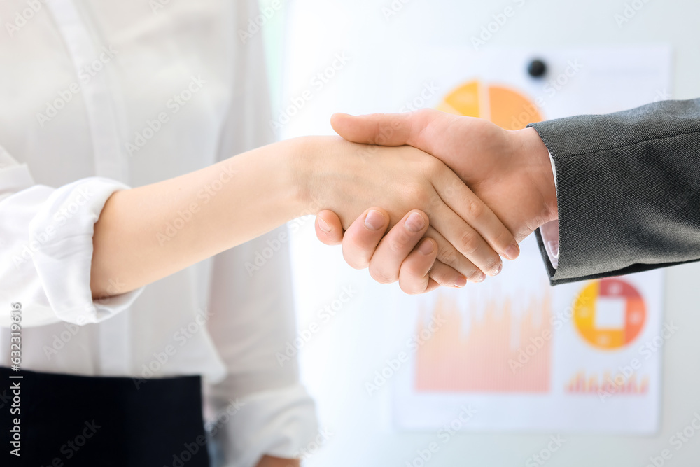 Business consultants shaking hands in office, closeup