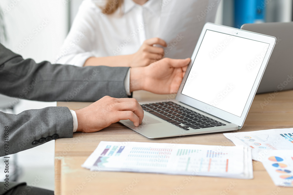 Male business consultant working with laptop at table in office, closeup