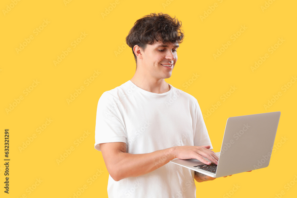 Male programmer working with laptop on yellow background