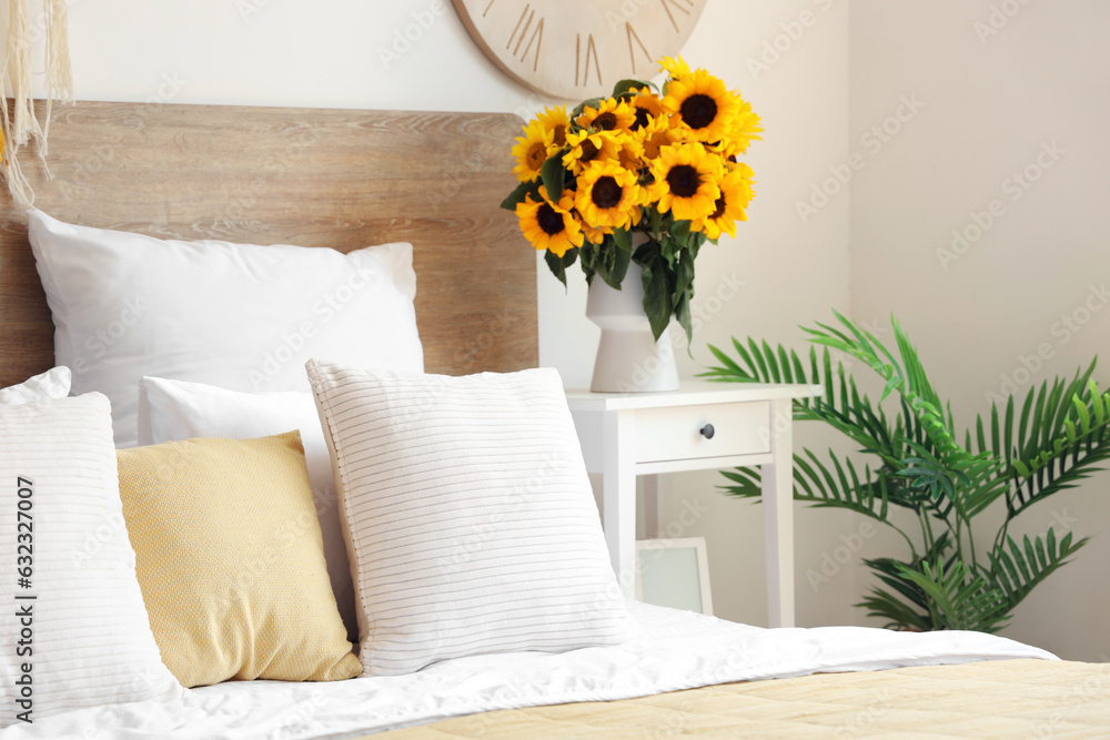 Vase with sunflowers on table in light bedroom