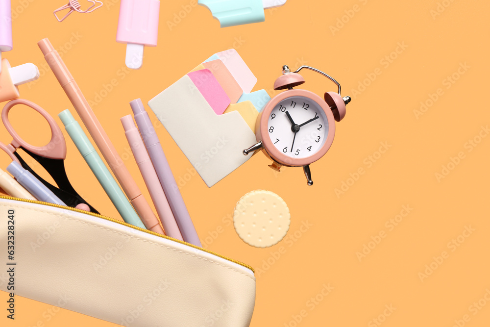 Pencil case with different stationery and alarm clock flying on color background