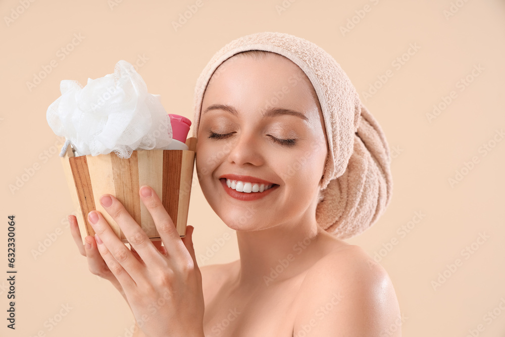 Pretty young woman with bath supplies on beige background