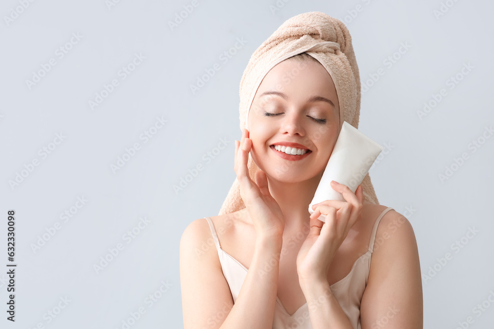 Pretty young woman after shower and with lotion on light background