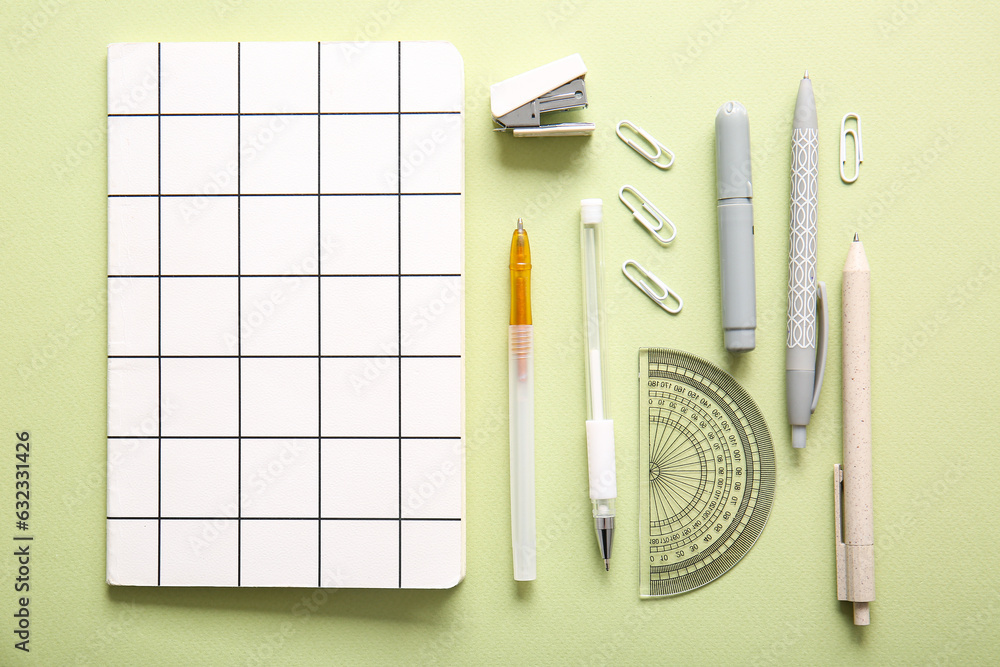 Different school stationery and notebook on green background