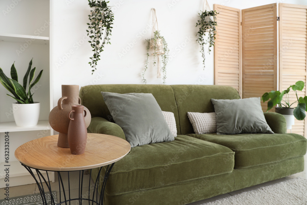 Interior of light living room with sofa, table and houseplants