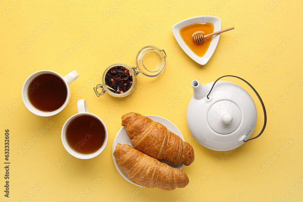 Composition with cups of tea, honey and croissants on yellow background