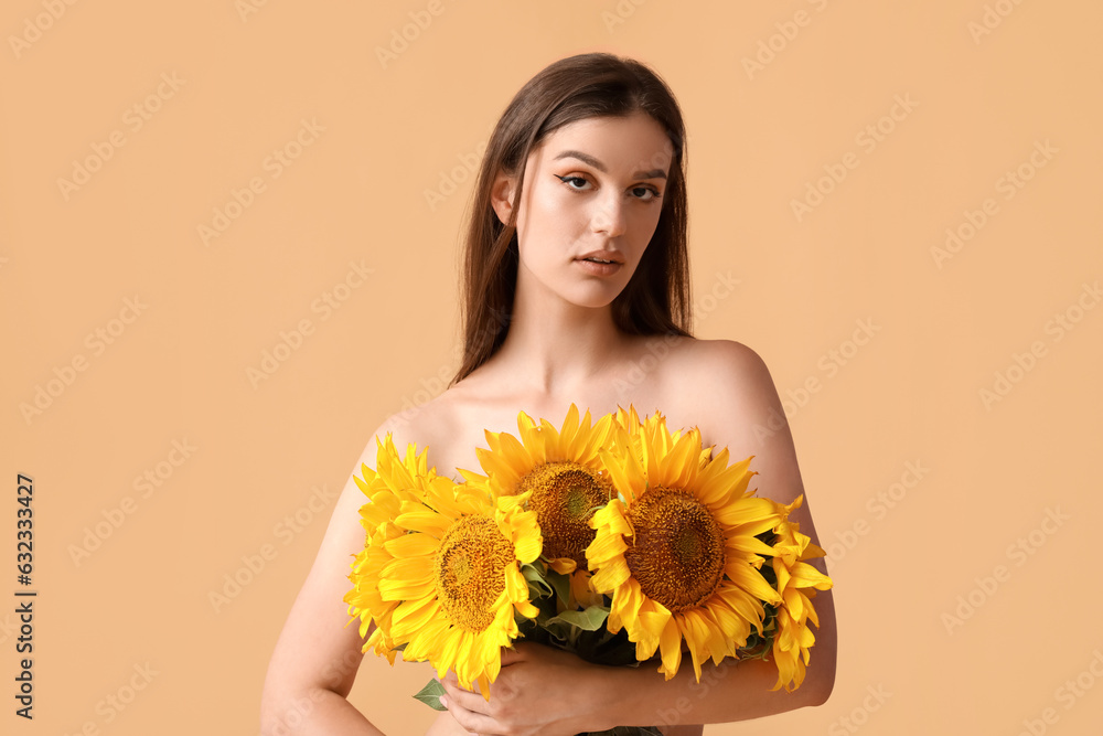 Young woman in underwear with bouquet of beautiful sunflowers on orange background