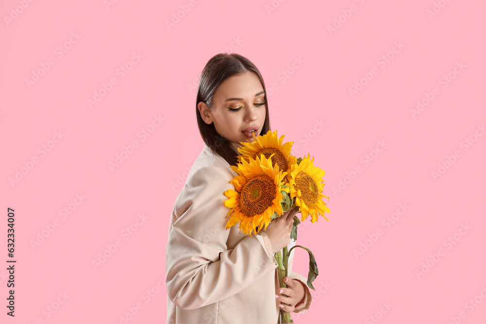 Young woman with bouquet of beautiful sunflowers on pink background