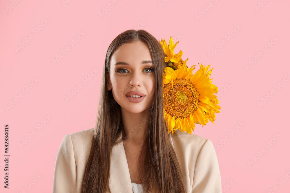 Young happy woman with bouquet of beautiful sunflowers on pink background