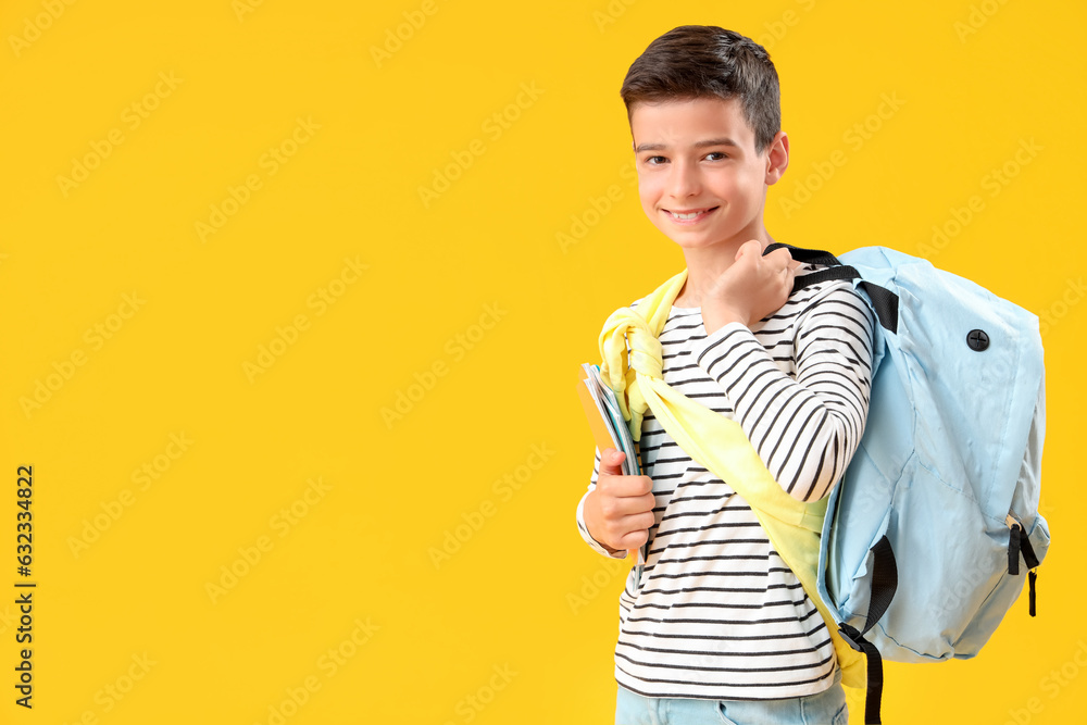 Portrait of happy schoolboy with backpack on orange background