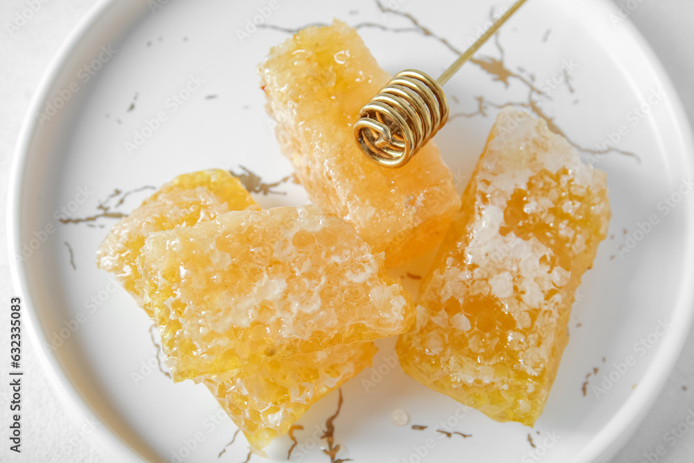 Plate with fresh honeycombs and dipper on light background, closeup