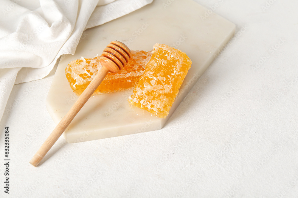 Board with fresh honeycombs and dipper on light background