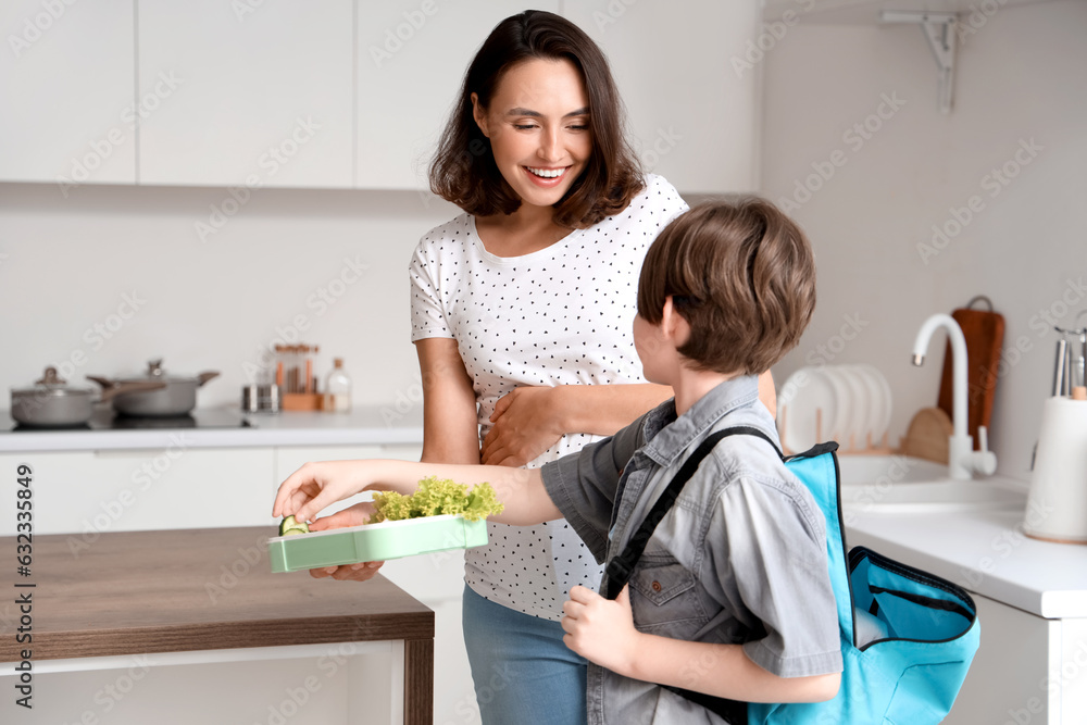 Mother giving tasty lunch to her son for school in kitchen