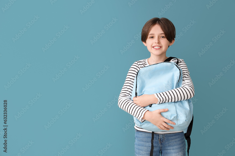 Happy little boy with backpack on blue background