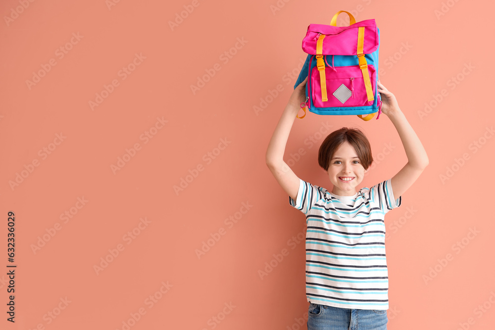 Happy little boy with backpack on color background