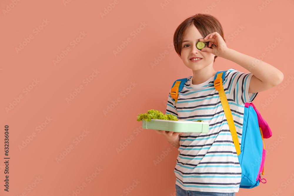 Happy little boy with backpack and lunchbox on color background