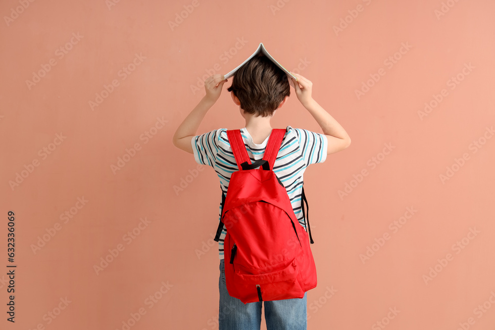 Little boy with backpack and notebook on color background, back view