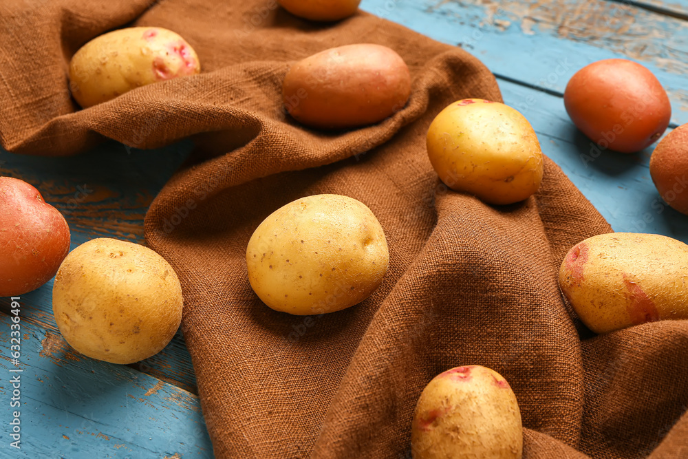 Fresh raw potatoes on blue wooden background