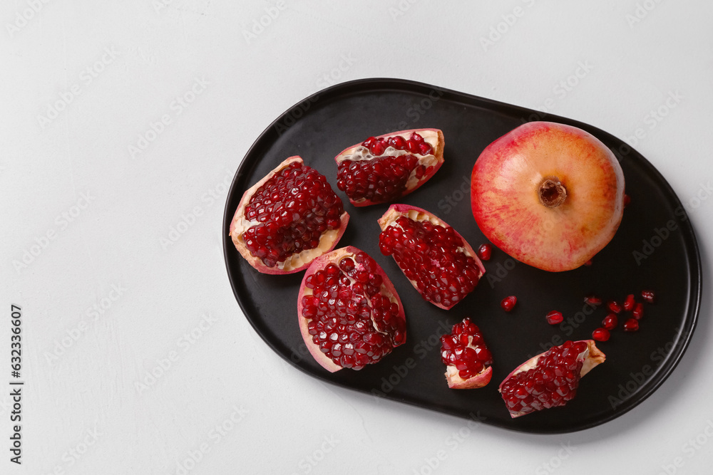 Plate with fresh pomegranates on white background