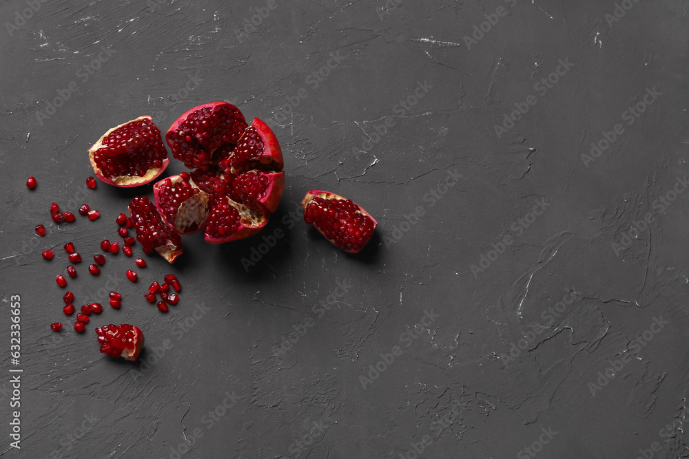 Pieces of fresh pomegranates with seeds on black background