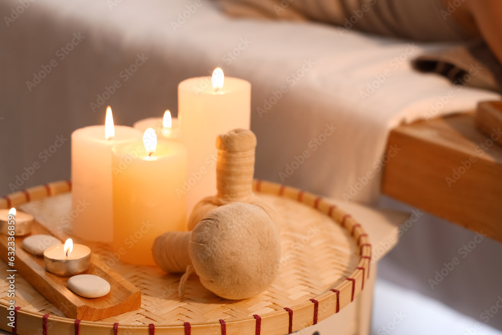 Burning candles and herbal bags on table in spa salon