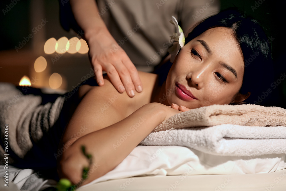 Pretty young Asian woman having massage in spa salon